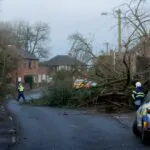flooding on a uk road with emergency response vehicles and warning signs during storm floris