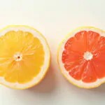 fresh pink grapefruit cut in half with elegant French text overlay showing pamplemousse pronunciation and meaning